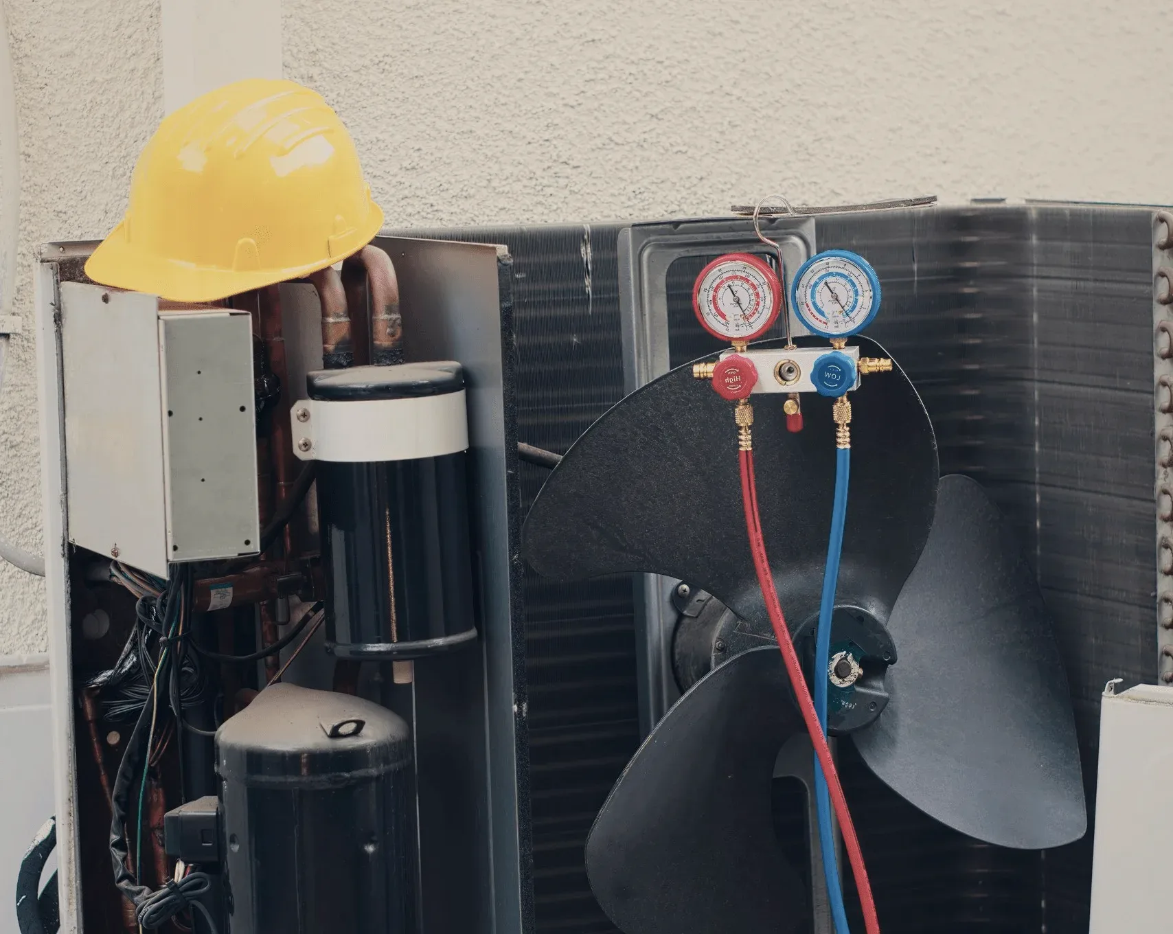 A pressure gauge set clipped to an outdoor unit.