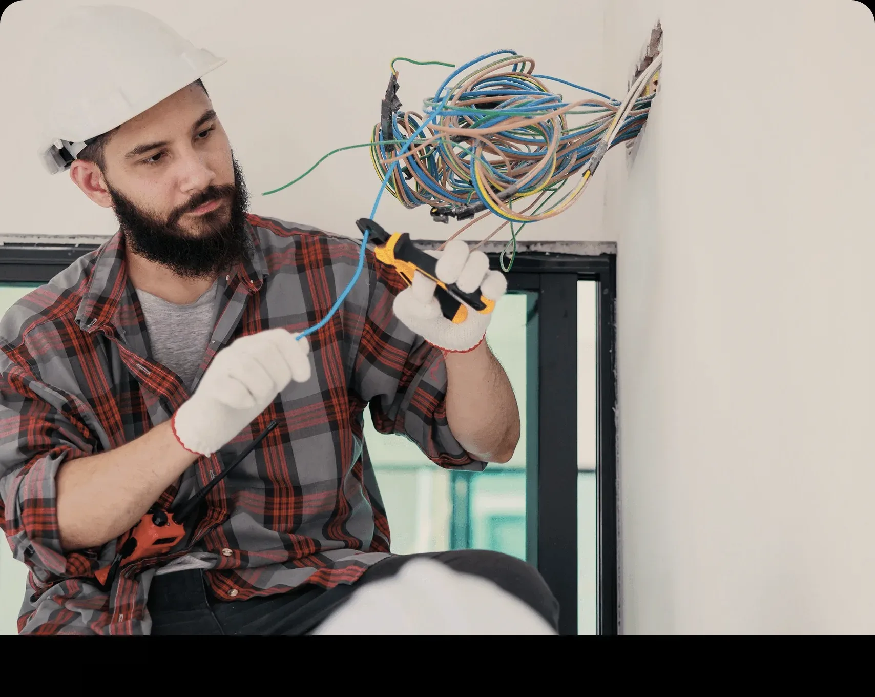 A technician stripping wires at a wall box.