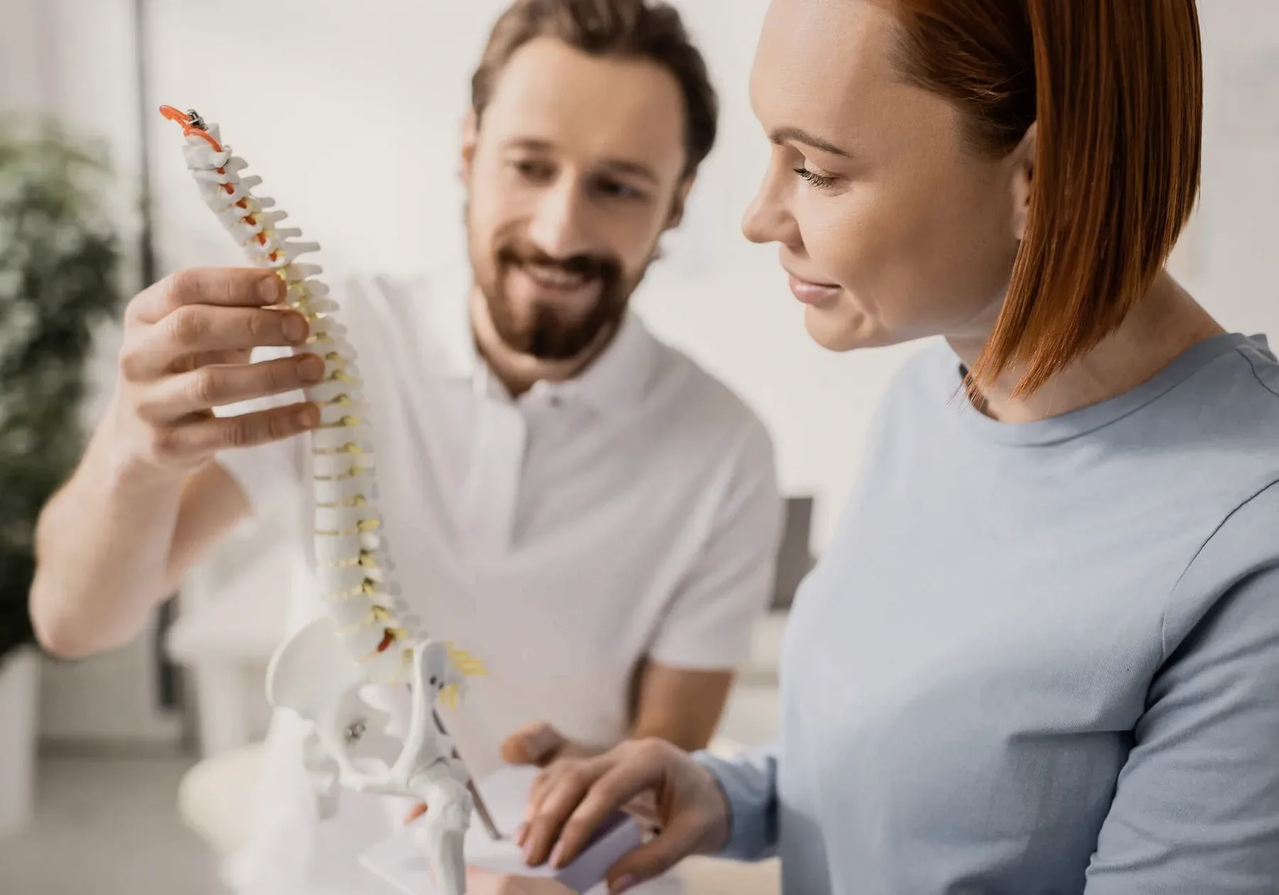 A chiropractor showing a spine model to a patient.