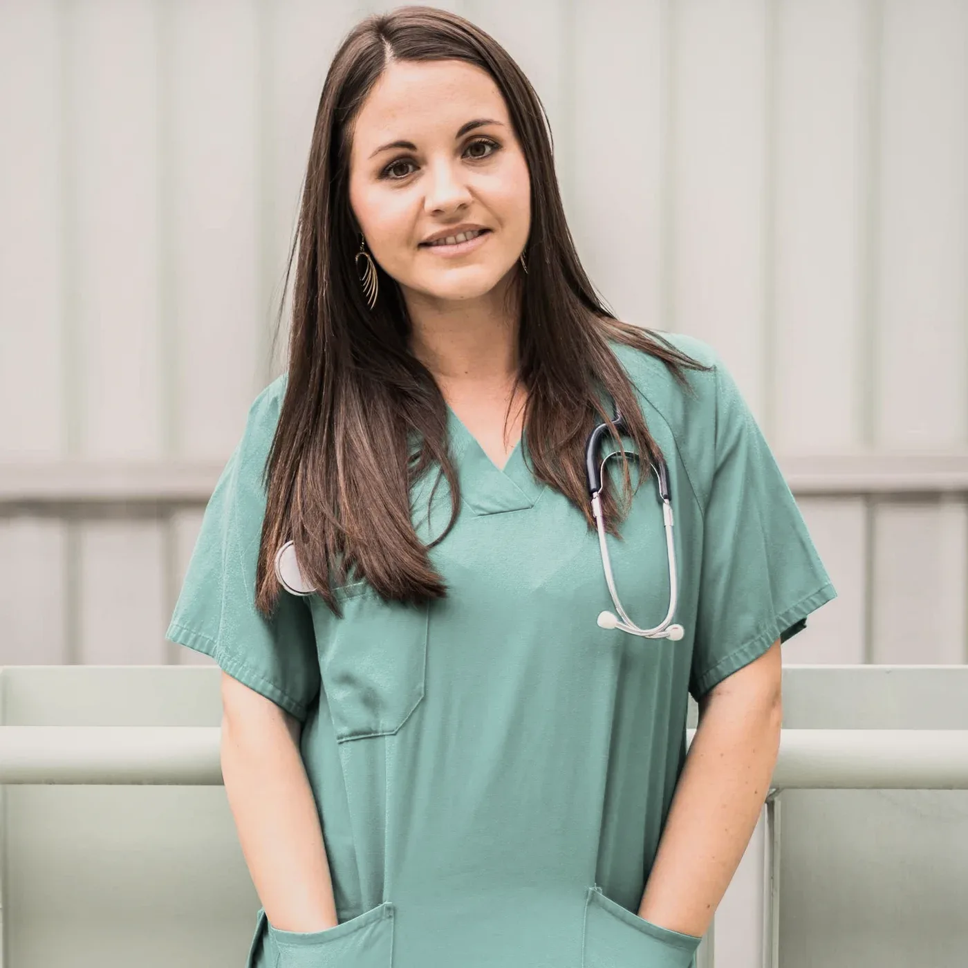 A smiling woman in green scrubs.