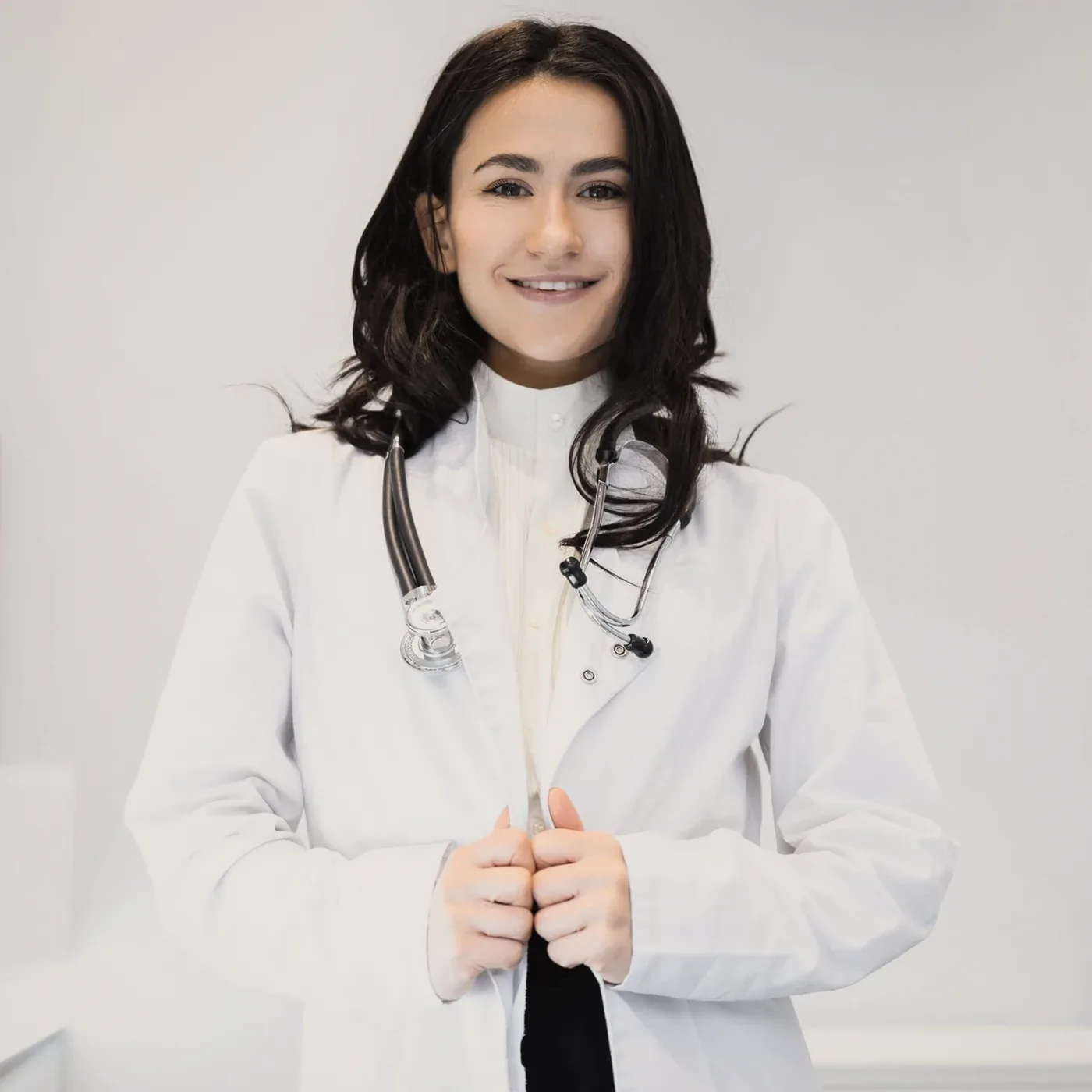 A smiling woman in a white coat.