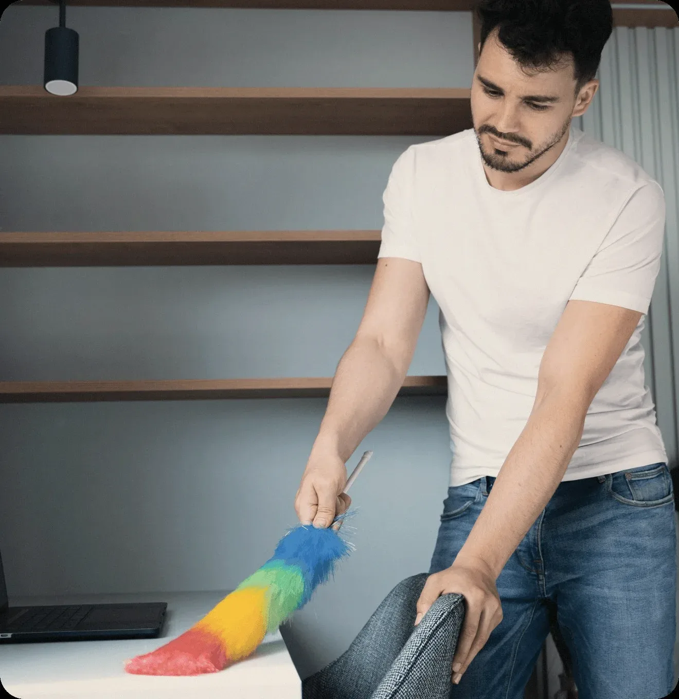 A cleaner dusting a shelf with a feather duster.