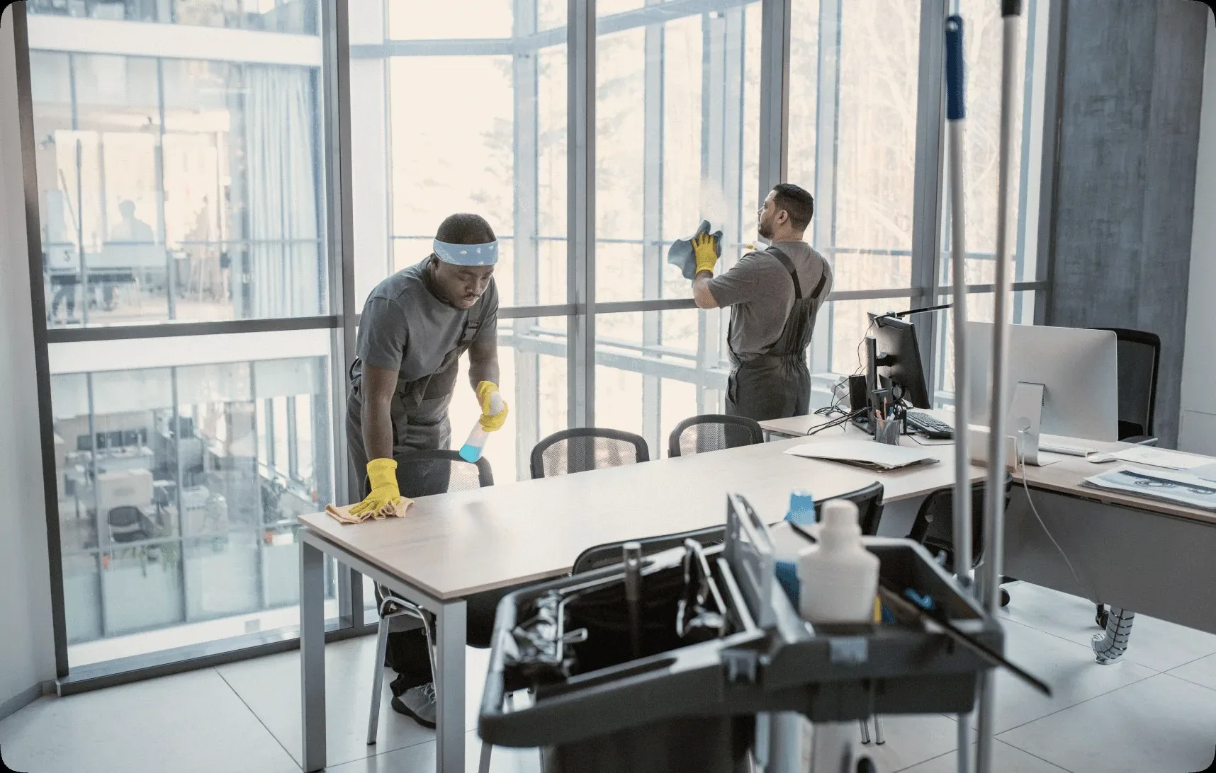 Two cleaners in a glass-walled office.