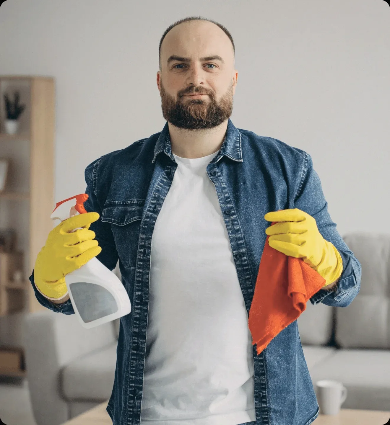 A cleaner in a denim shirt holding a spray and a cloth.