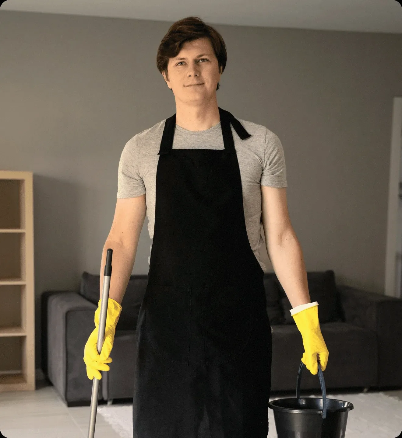 A cleaner in a black apron with a bucket and a mop.