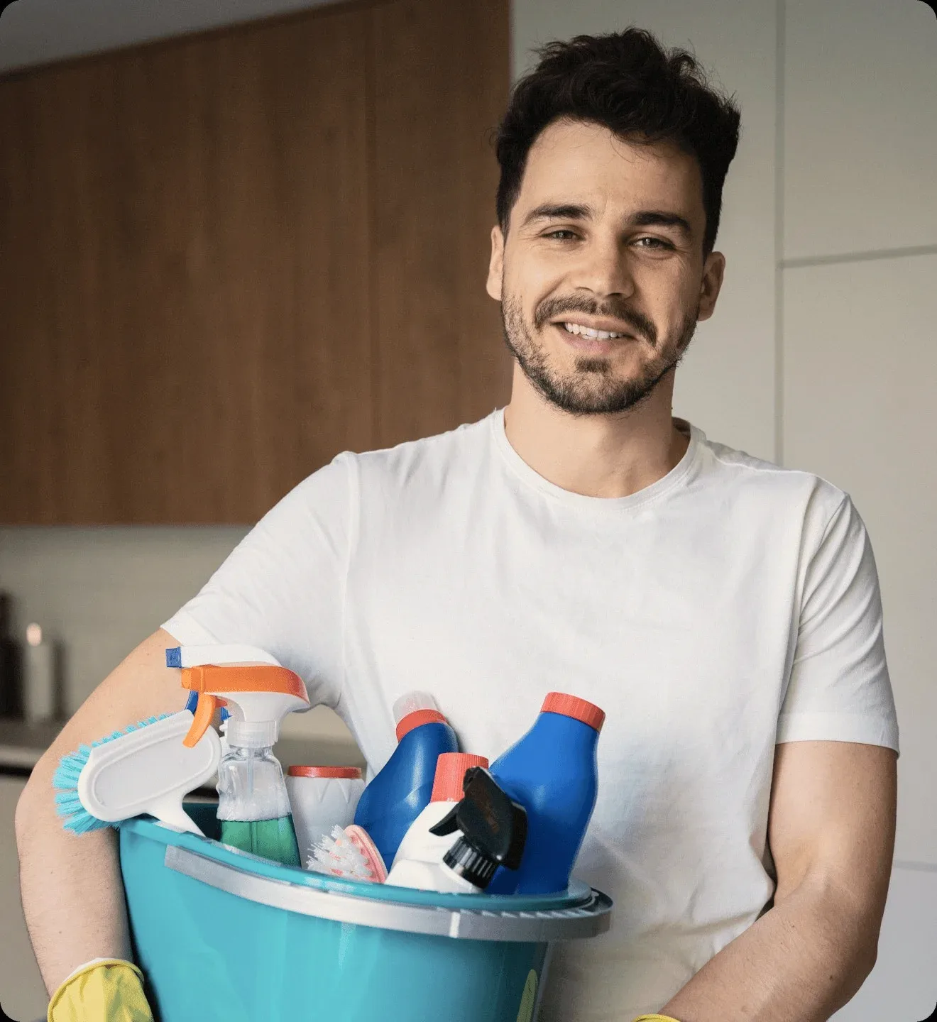 A cleaner holding a bucket of bottles and gloves.
