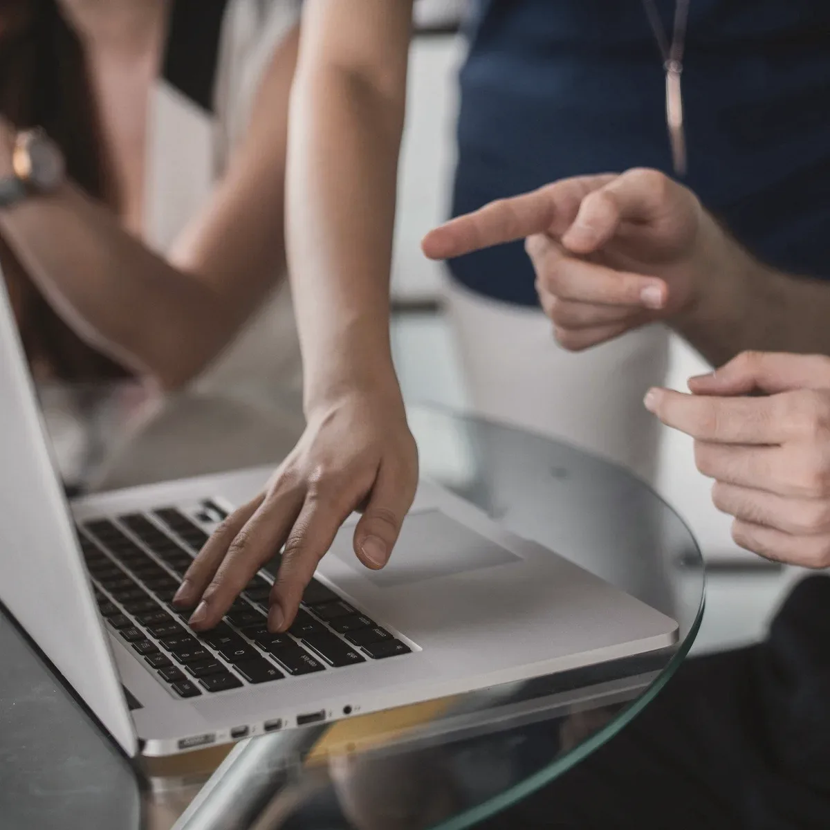 Hands pointing at a laptop screen.