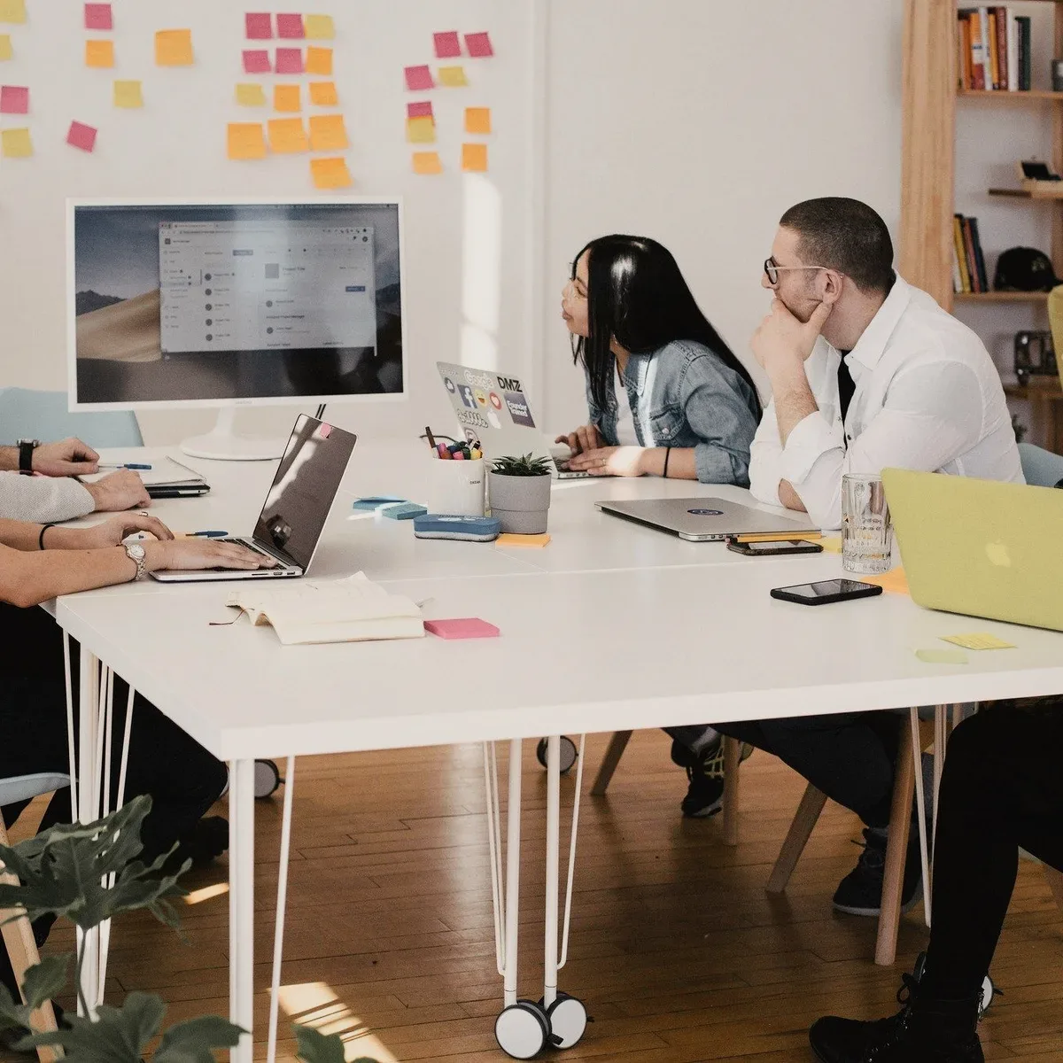 A team at a table under a wall of sticky notes.