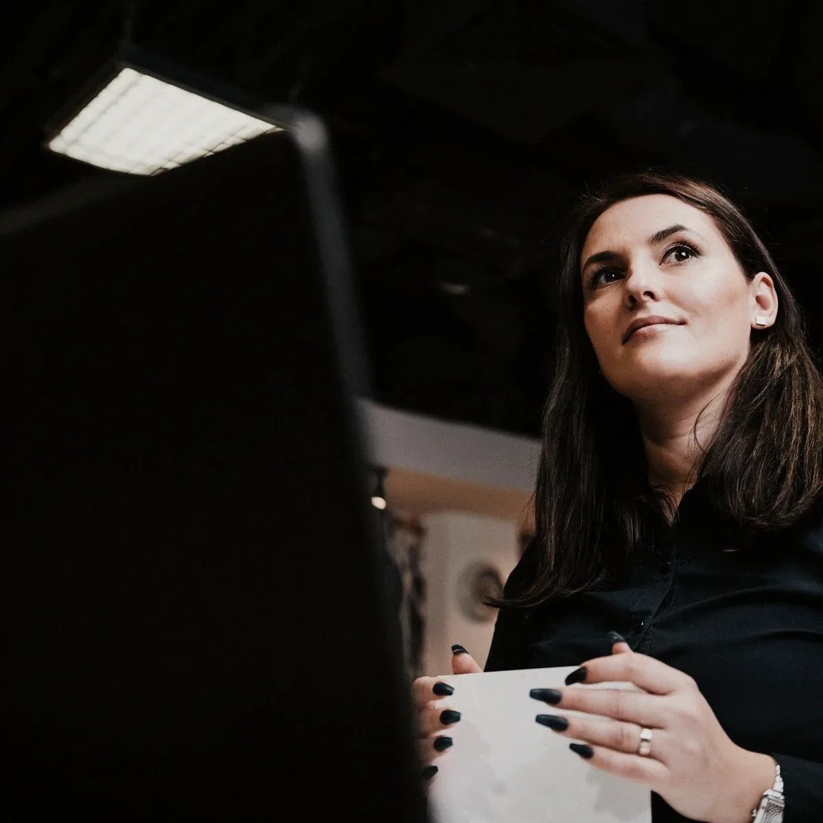 A woman looking up in a dark room.