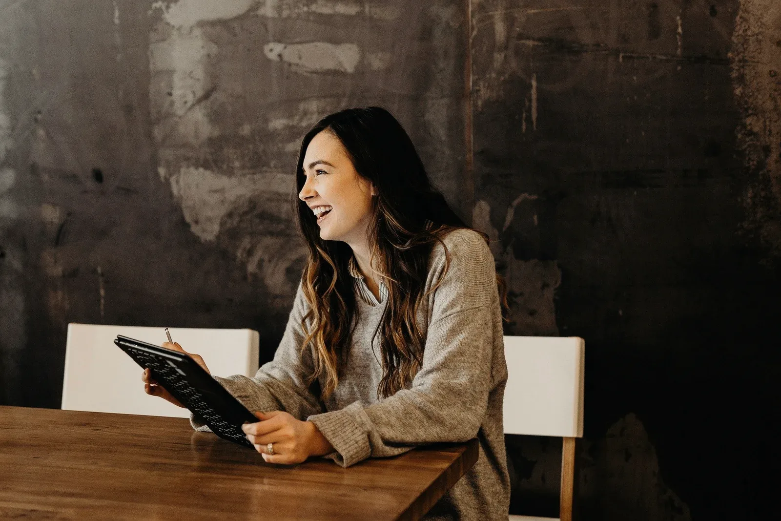 A consultant with a tablet, laughing at a cafe table.