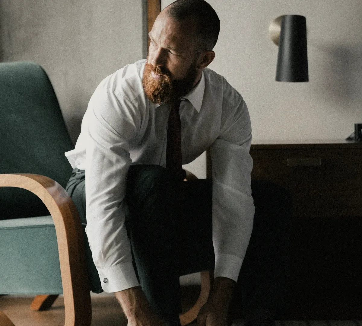 A bearded man in a white shirt leaning forward.