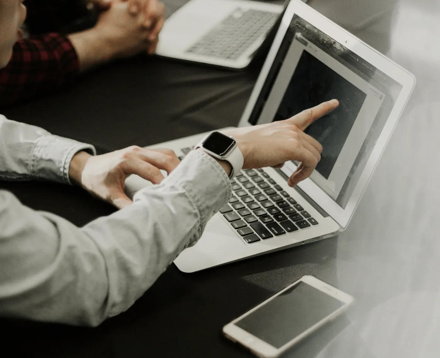 Hands on a laptop at a table.