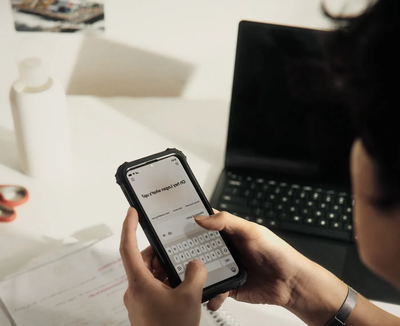 A phone held over a notebook.