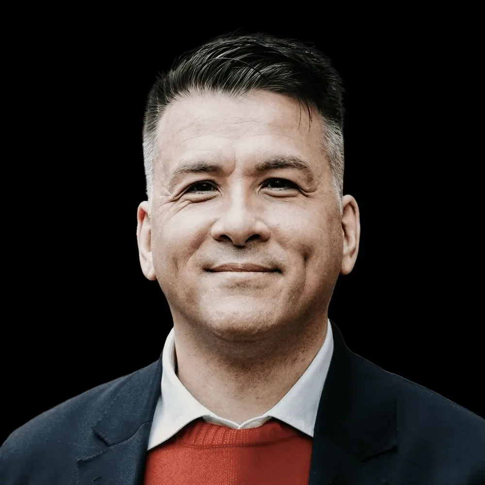 A man in a navy jacket and red jumper.