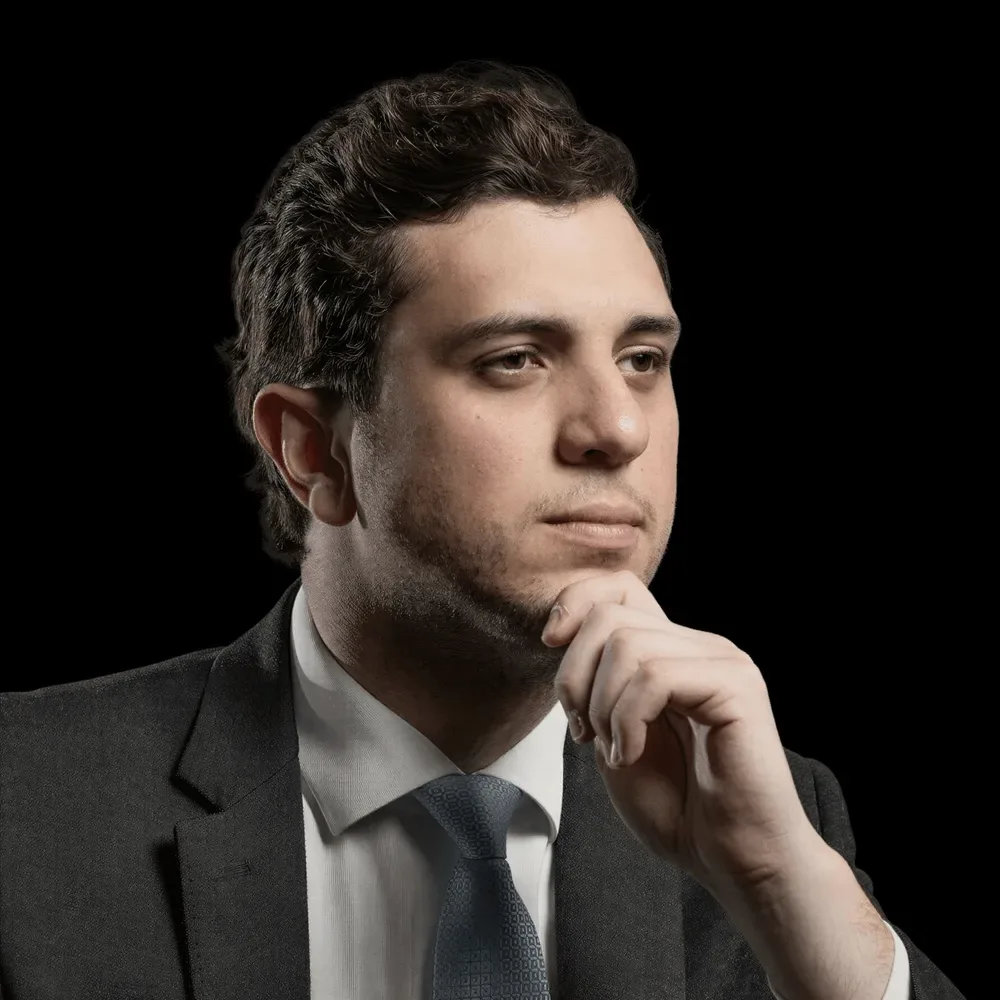 A man in a suit with a hand at his chin.