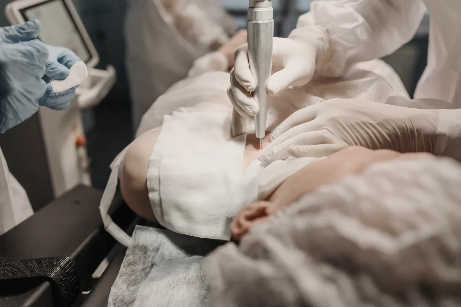 A clinician's gloved hands working with a handheld device, no procedure site in view.