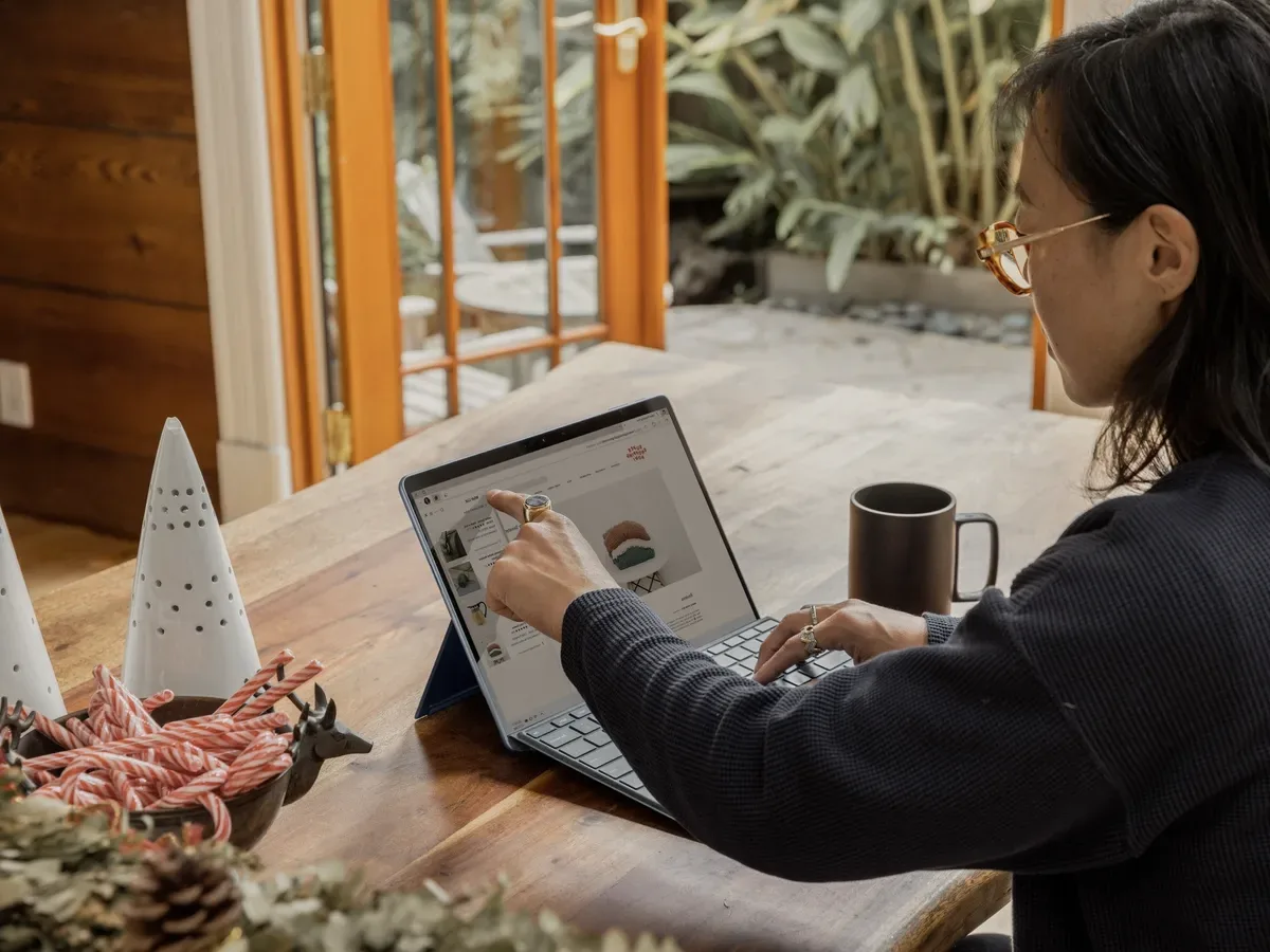 A woman at a laptop by an open window.