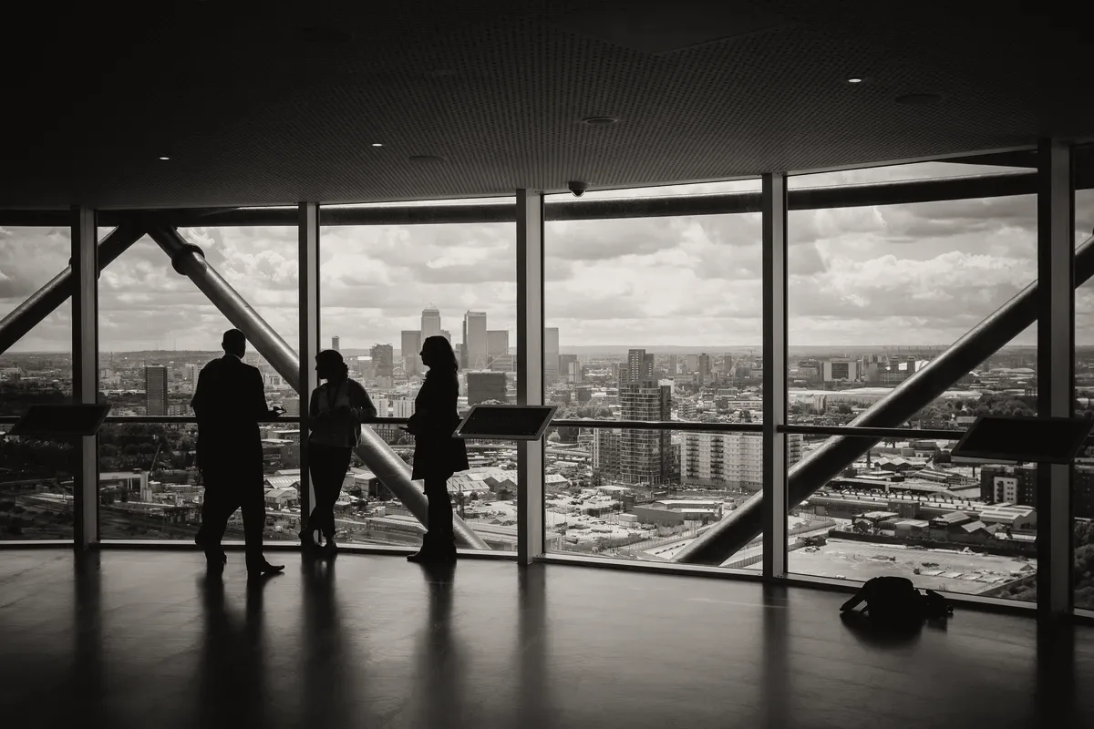 People in silhouette inside a glass building.