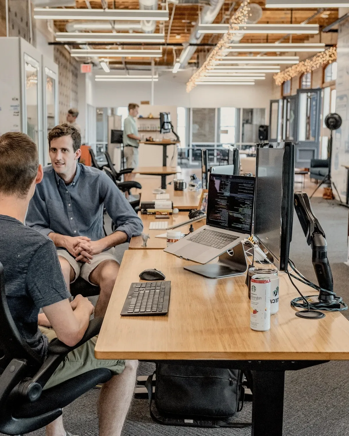 Three men in conversation at a desk.