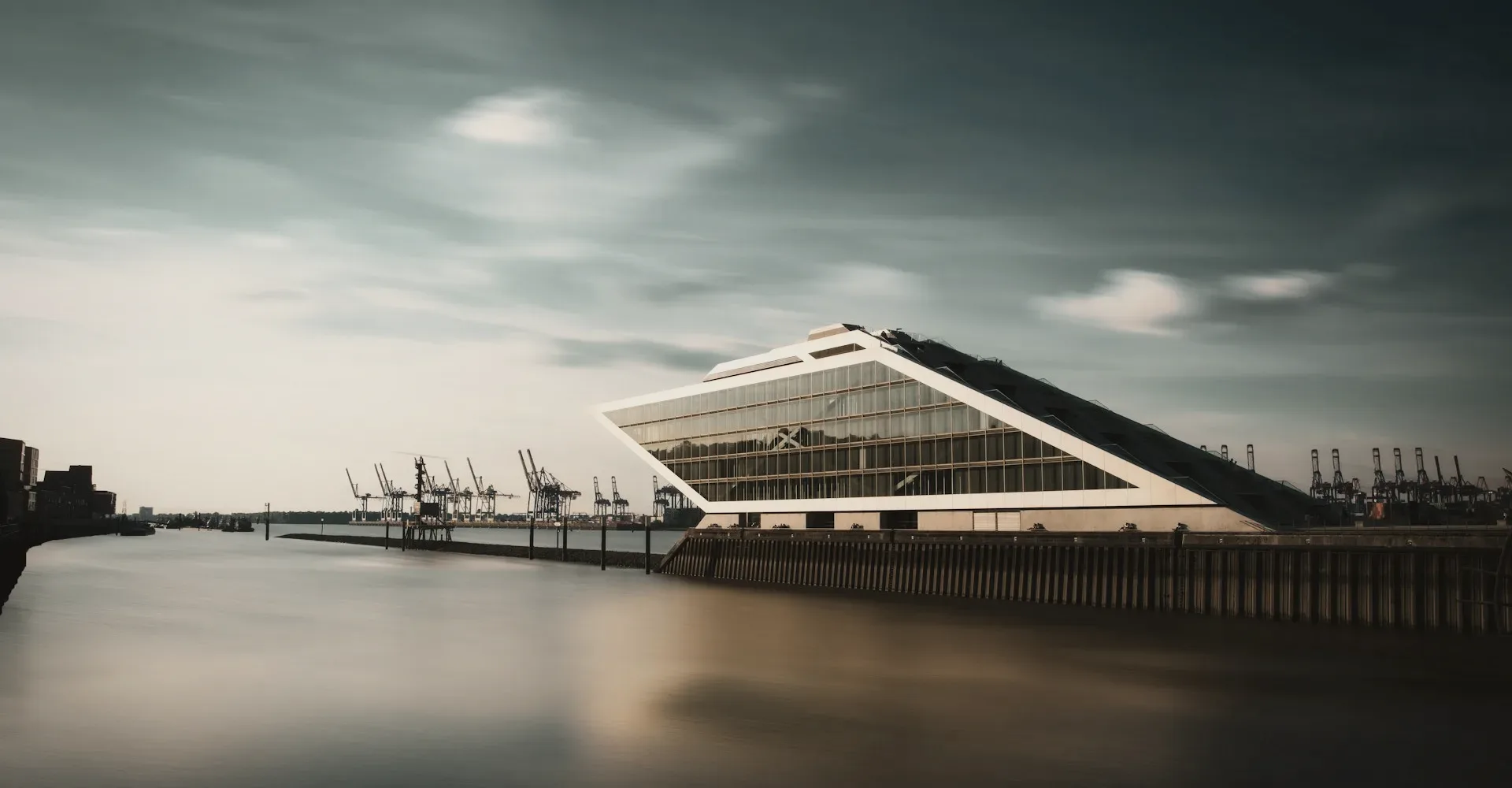 A glass terminal by a harbour at dusk.