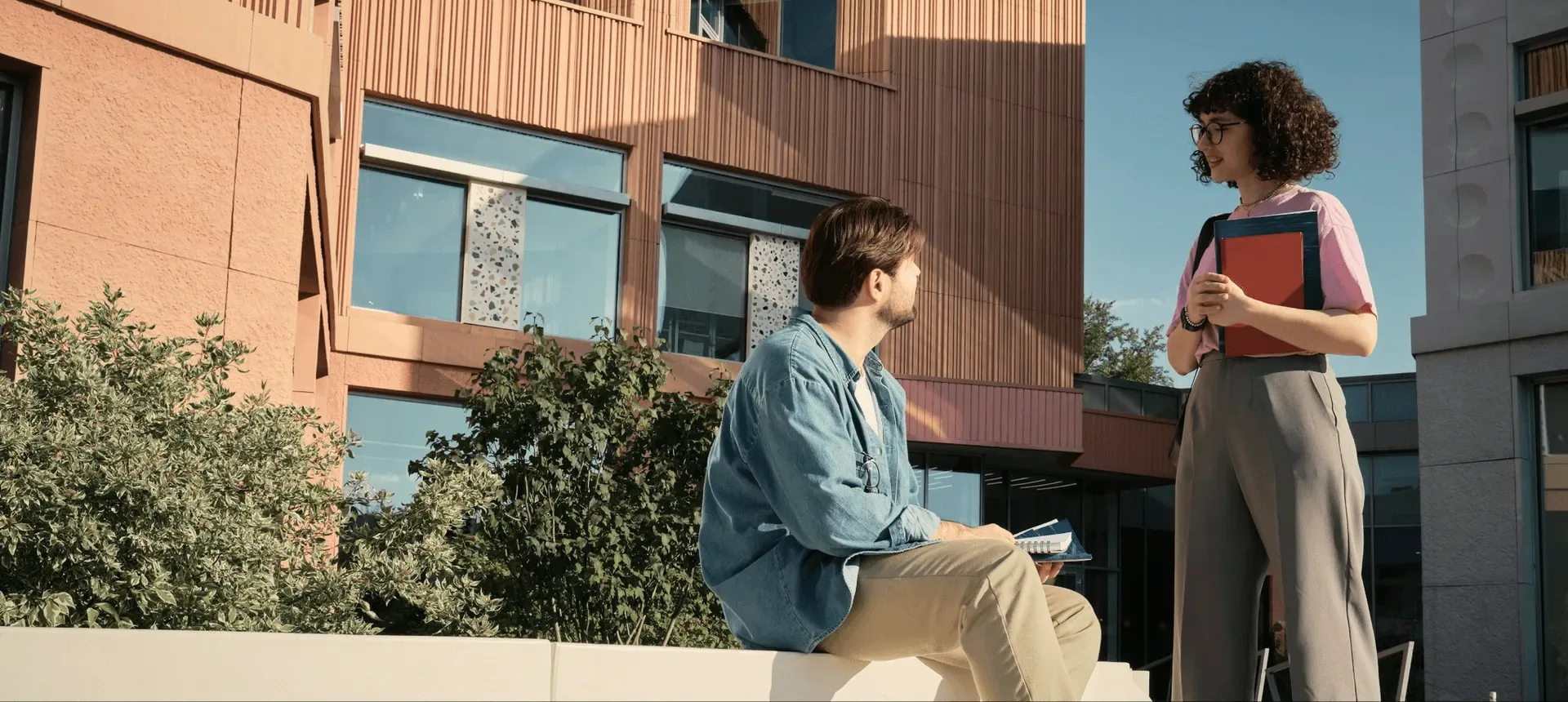 Two students talking on a campus bench.