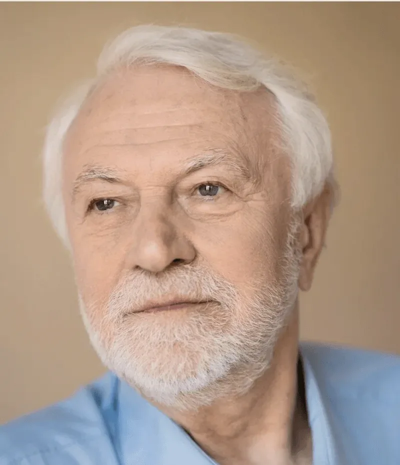 A white-bearded man in a blue shirt.
