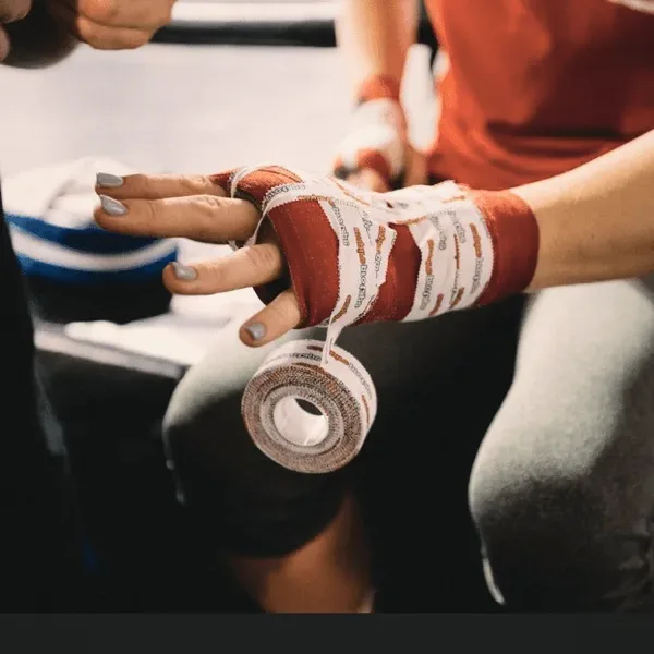 Hands wrapping a boxing glove.
