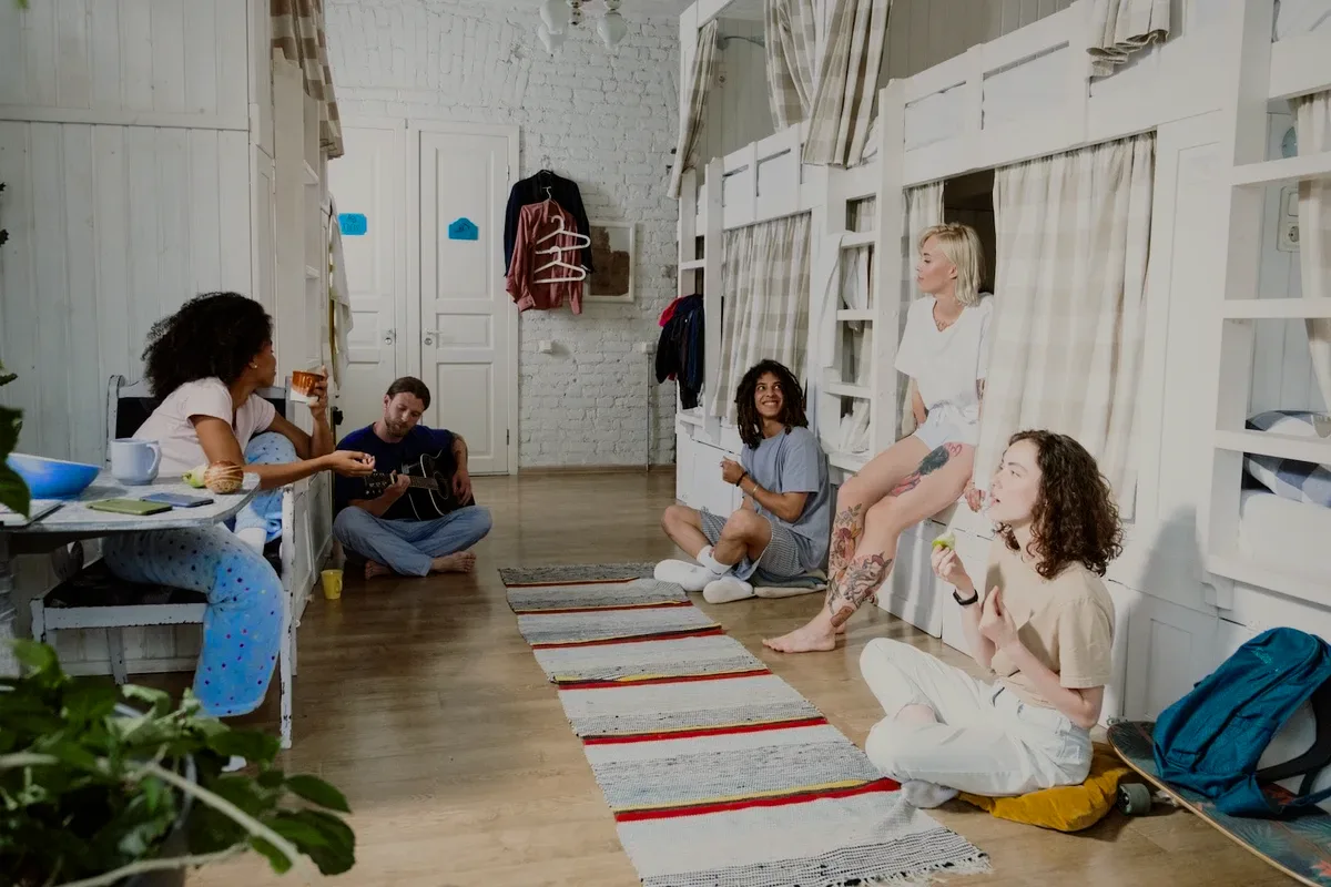 Guests sitting on the floor of a long dorm, talking.