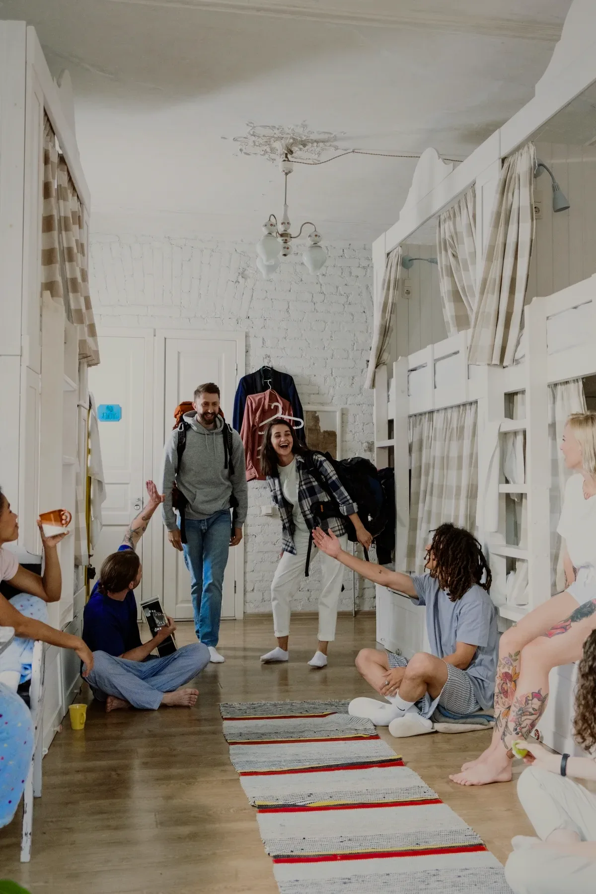 Backpackers meeting in a dorm with white bunk beds.