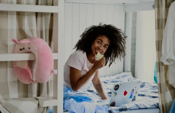 A woman eating an apple on a bunk bed.