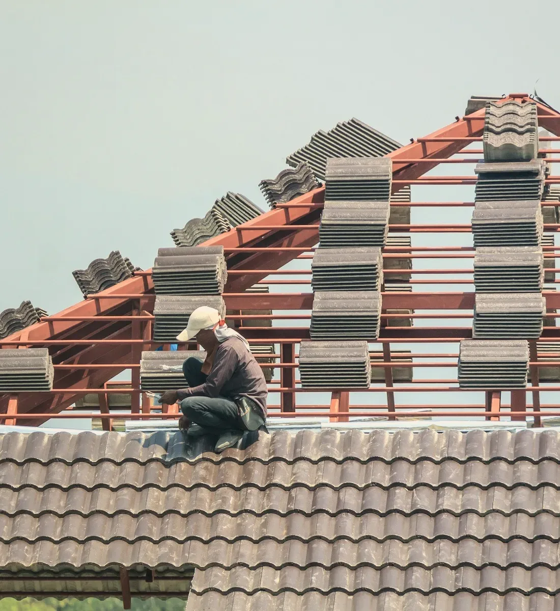A roofer laying tiles on a red frame.