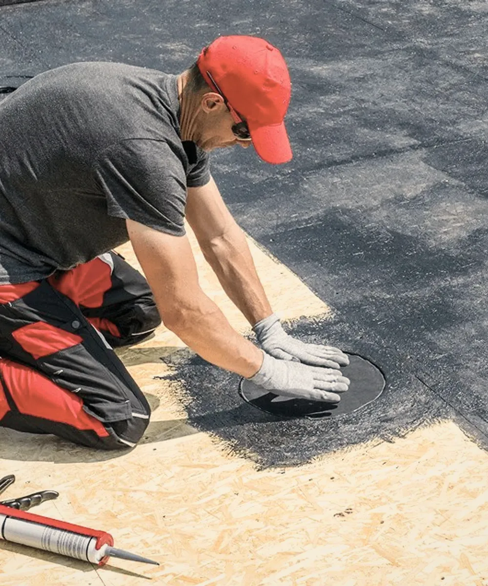 A roofer in a red cap on a flat roof.
