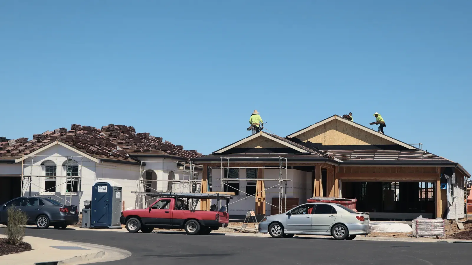 A house being re-roofed, seen from the street, with workers along the roof slope.