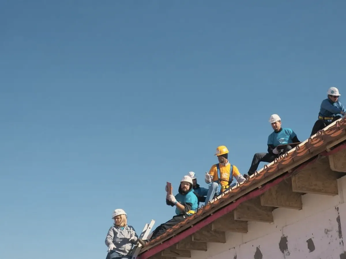 A crew in helmets along a roof edge.