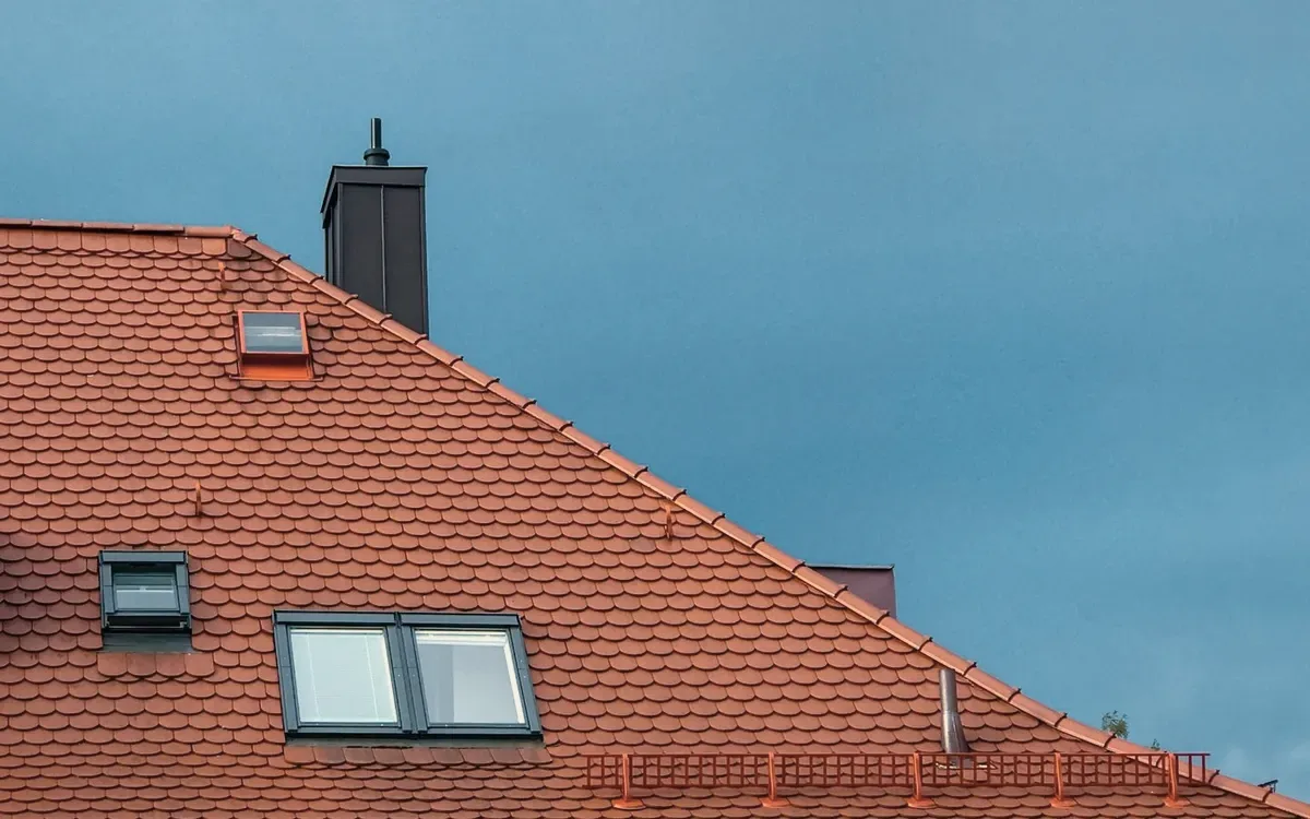 A red tiled roof with skylights against blue sky.