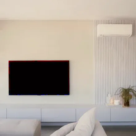 A living room with an air conditioner above a wall-mounted screen.