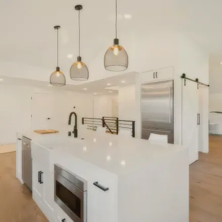 A white kitchen with a large island and pendant lights.