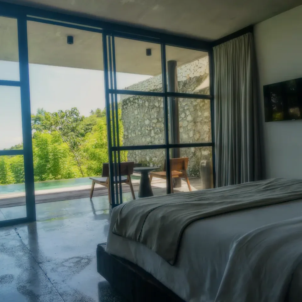 A bedroom with a wide bed facing glass doors onto a patio.