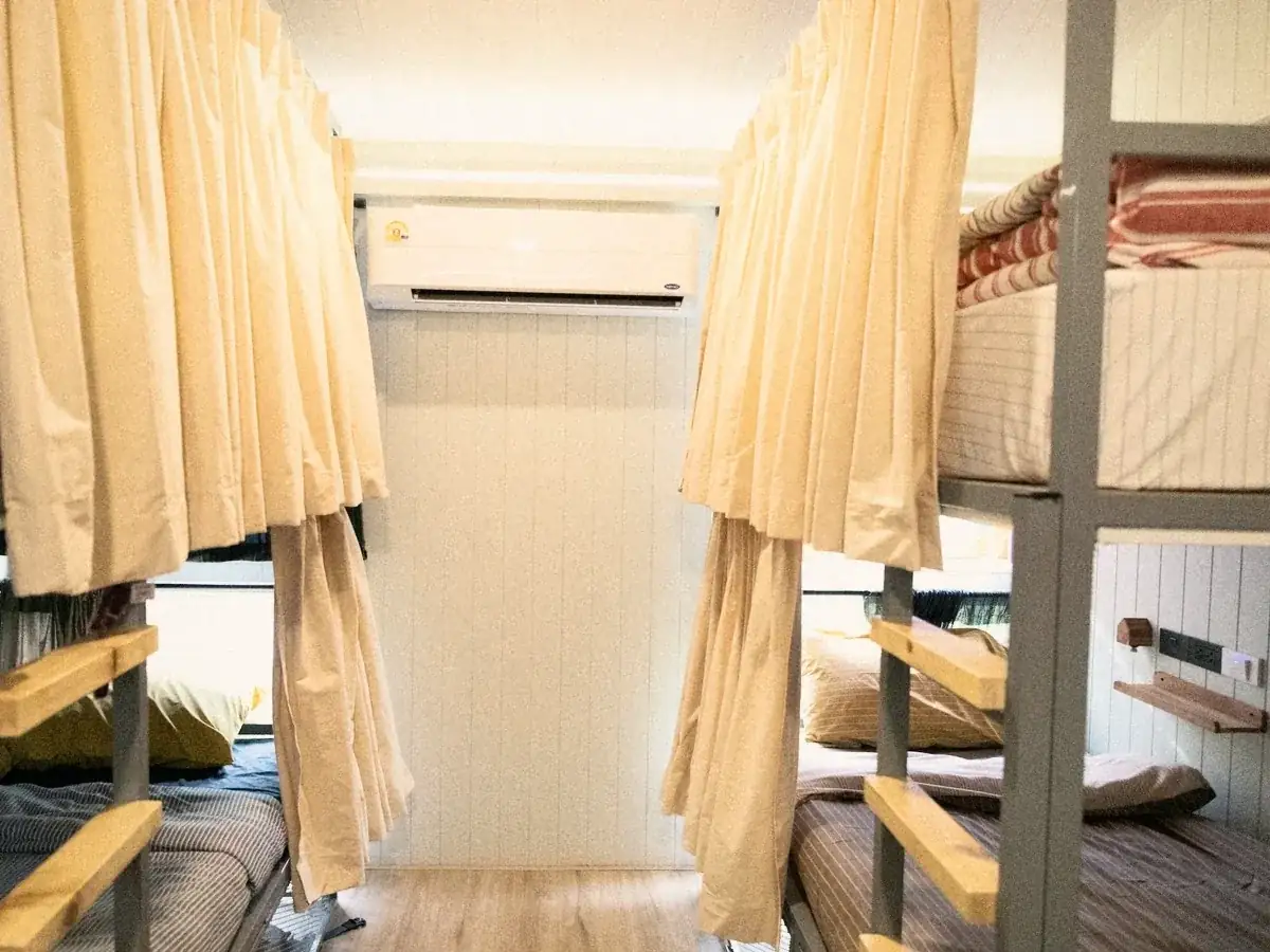 Curtained pod bunks in a dorm with wooden walls.
