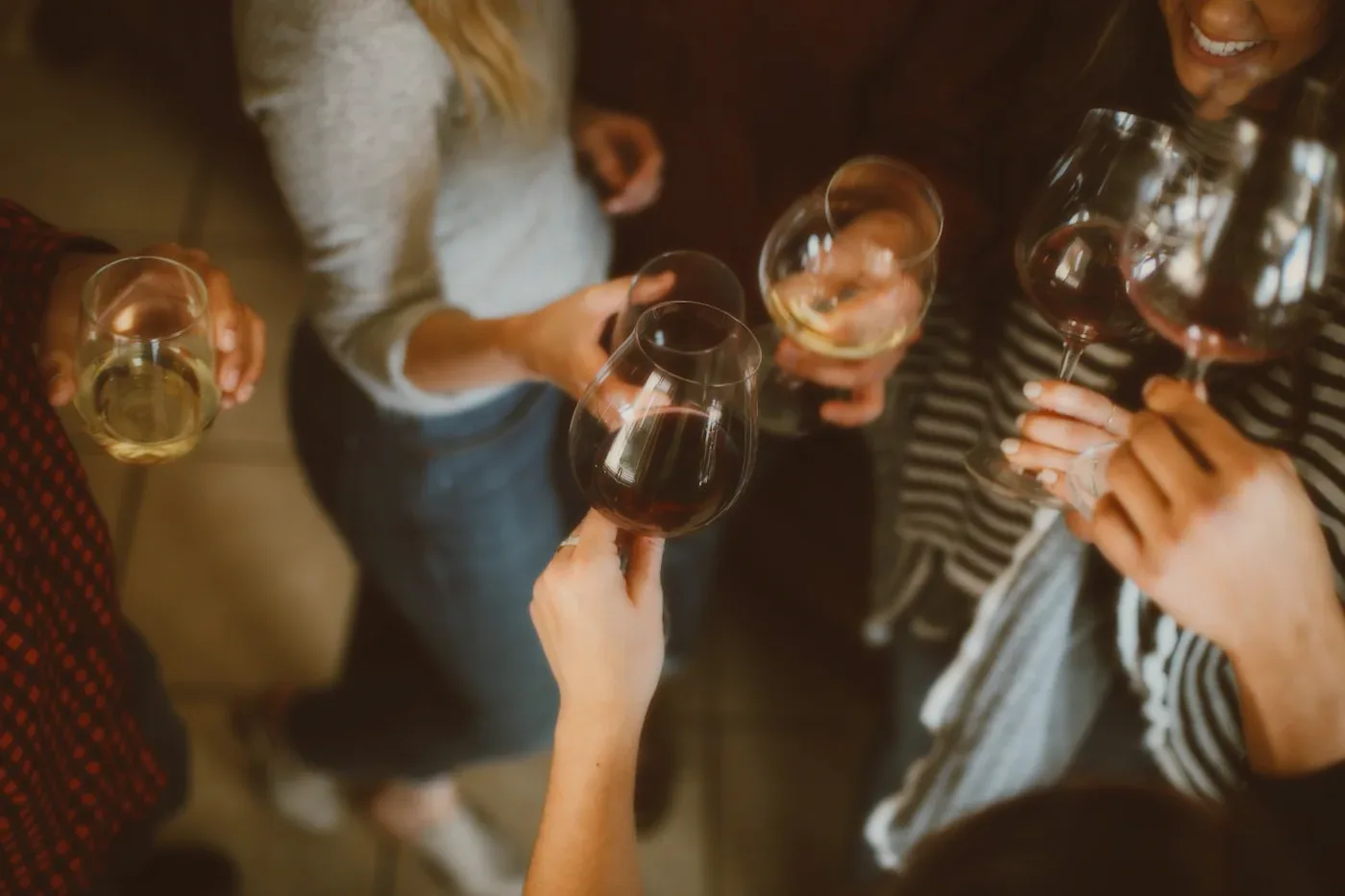 Hands raising wine glasses at a party.