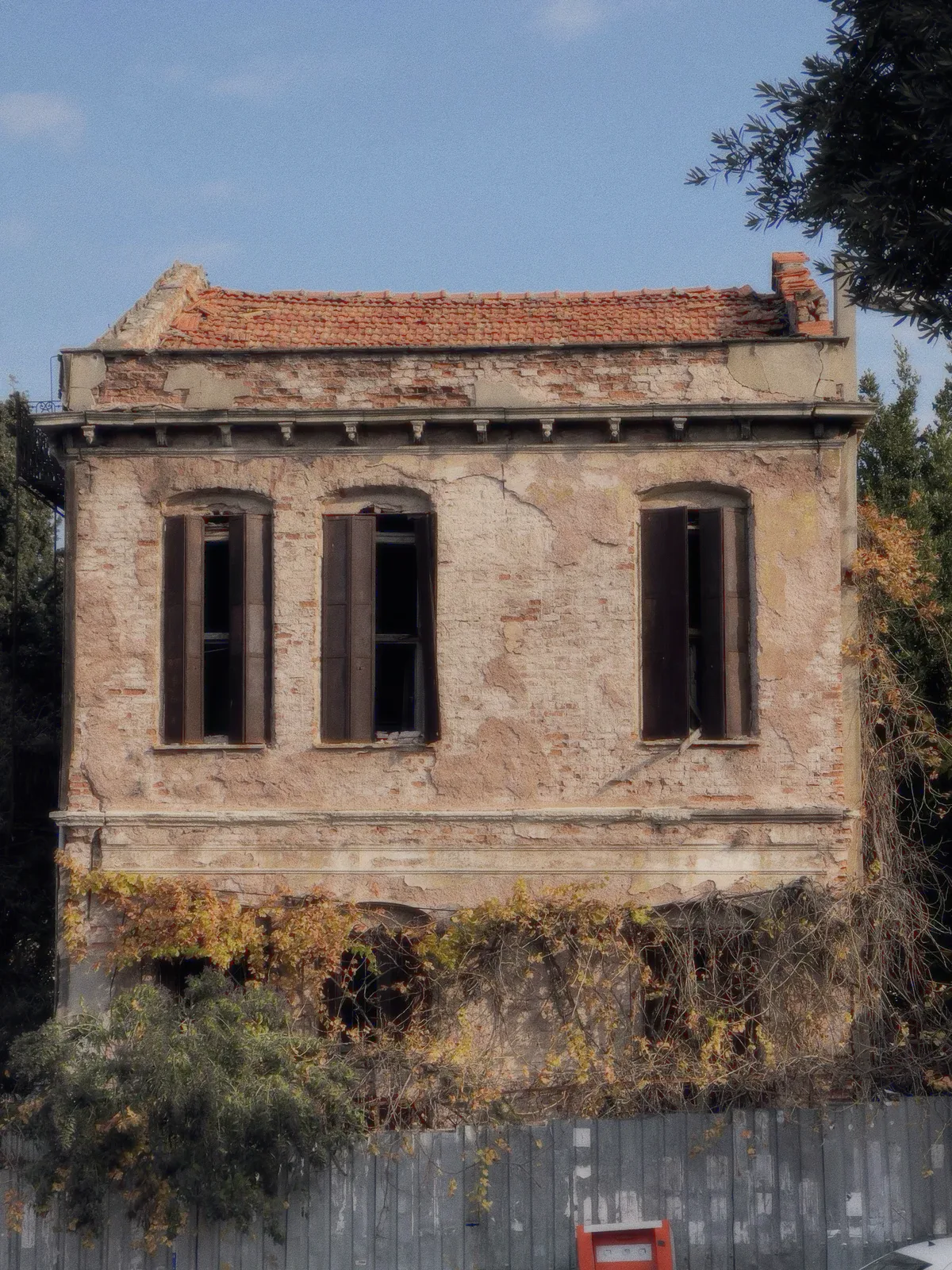 An old plastered facade with three shuttered windows.