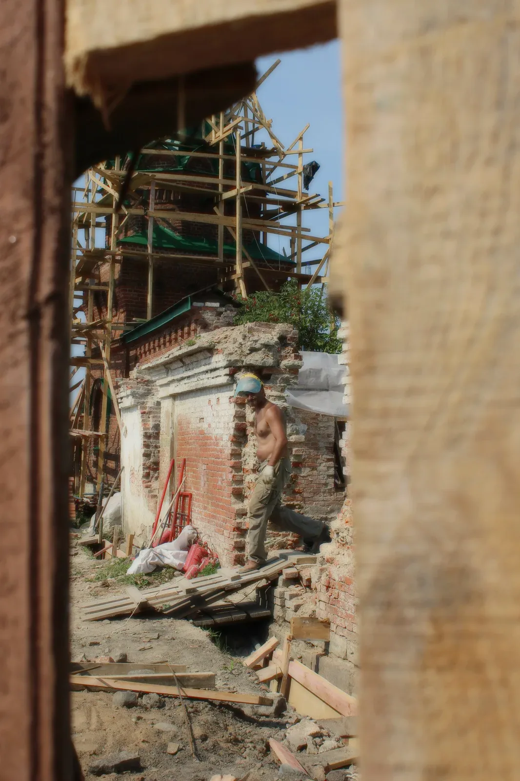 A worker on scaffolding at a brick wall.
