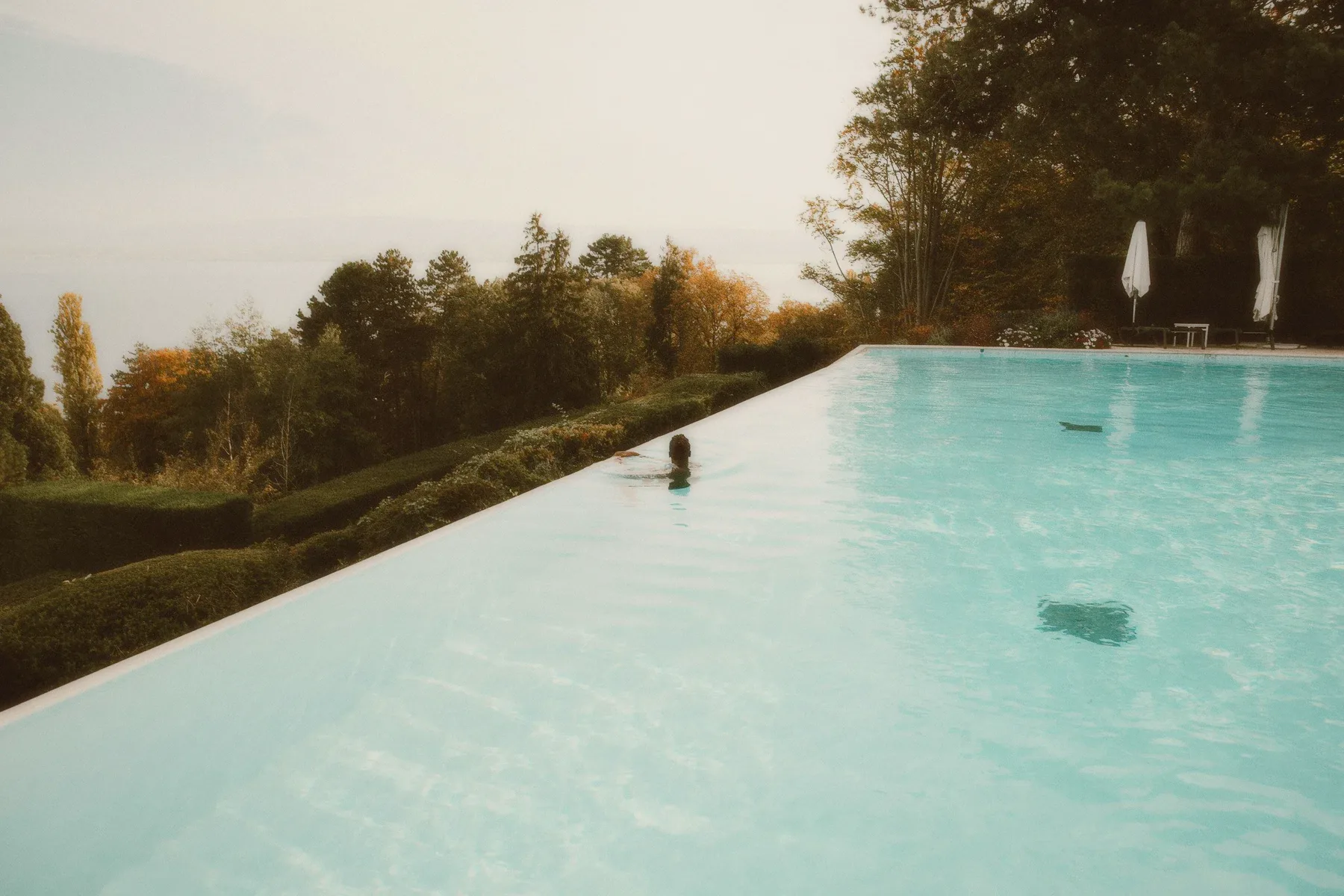 A swimmer in an infinity pool at the edge of a valley.