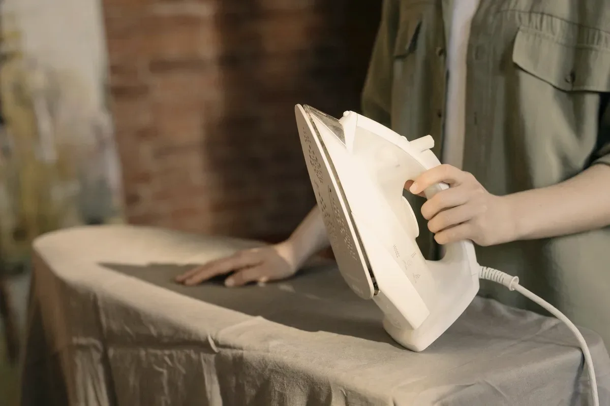 An iron on a shirt on an ironing board.