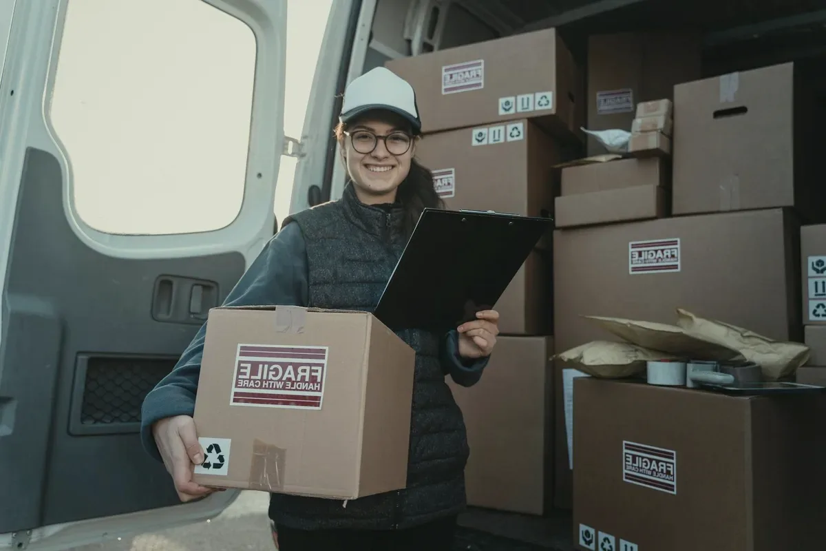 A courier with a parcel at a van door.