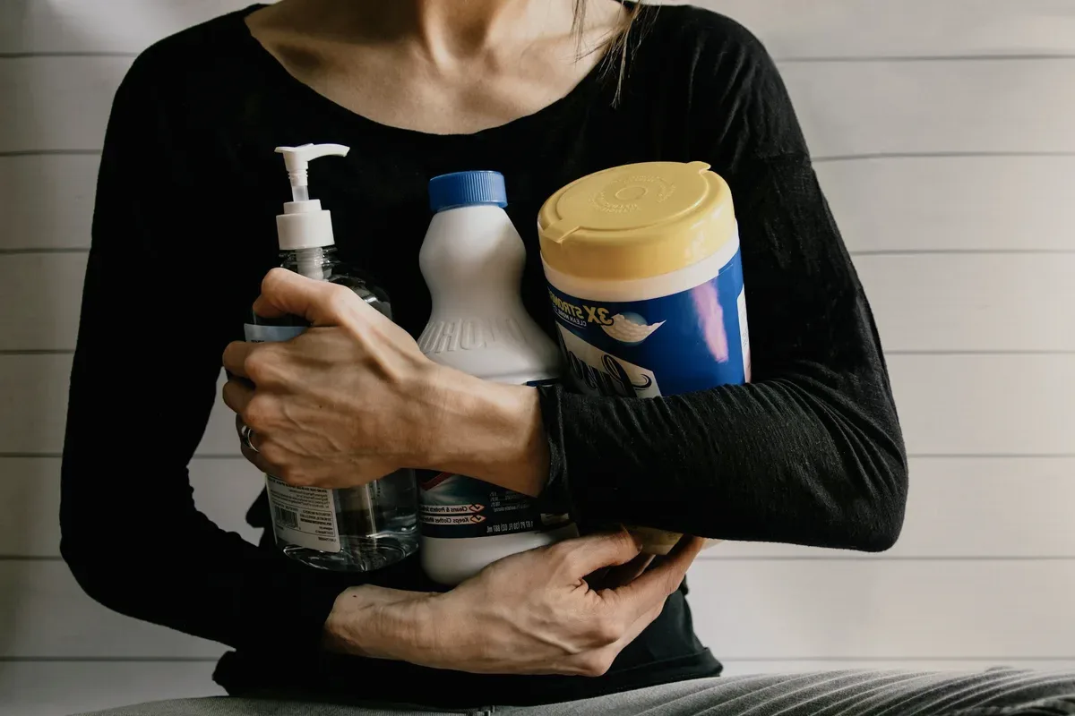 Arms holding cleaning bottles.
