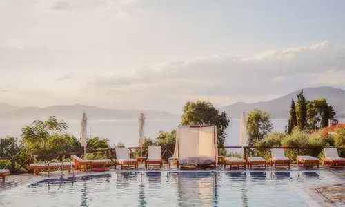 Sun loungers around a pool facing the sea at sunset.