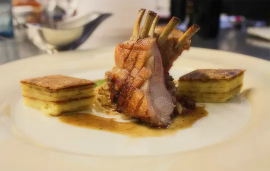 A plated lamb dish with sauce.