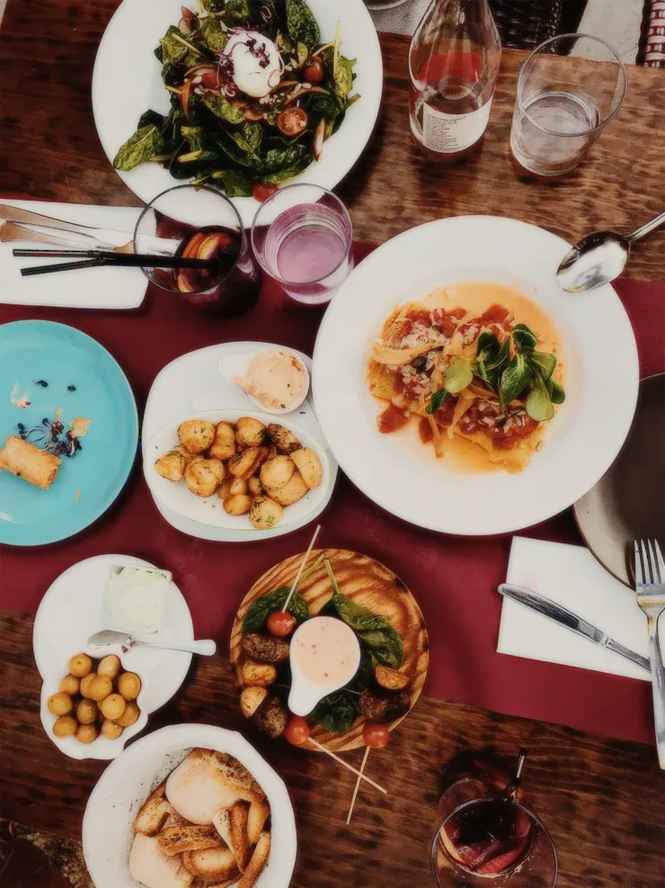 Plates of food and drinks on a red tablecloth.